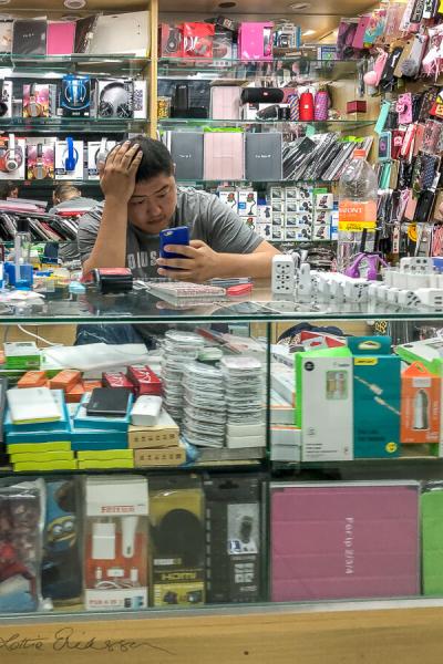 Saopaolo Indoor Market Stall Counter Salesman Checking Phone900 Saopaolo Indoor Market Stall Counter Salesman Checking Phone900